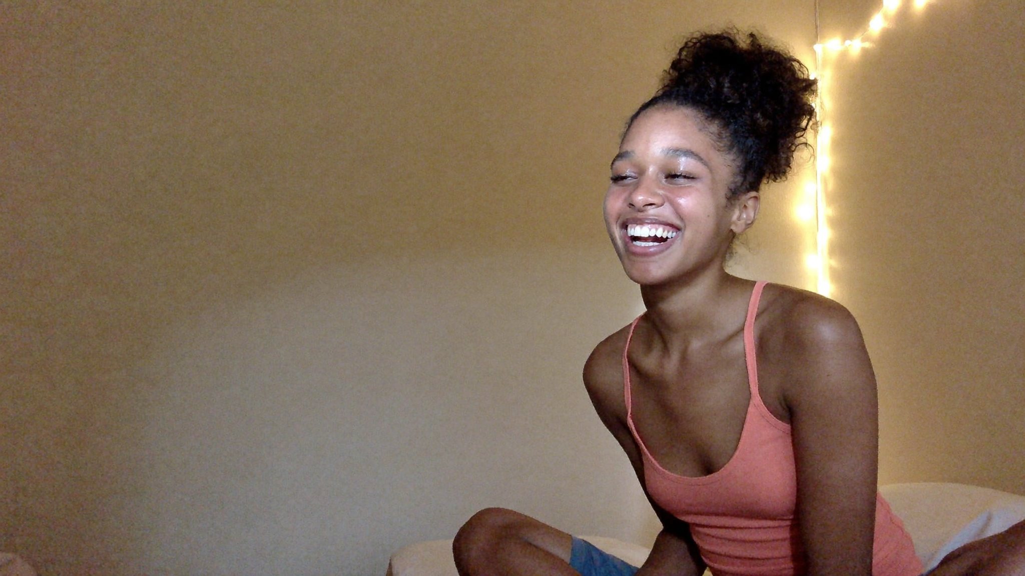 A Latina creator laughing in her room