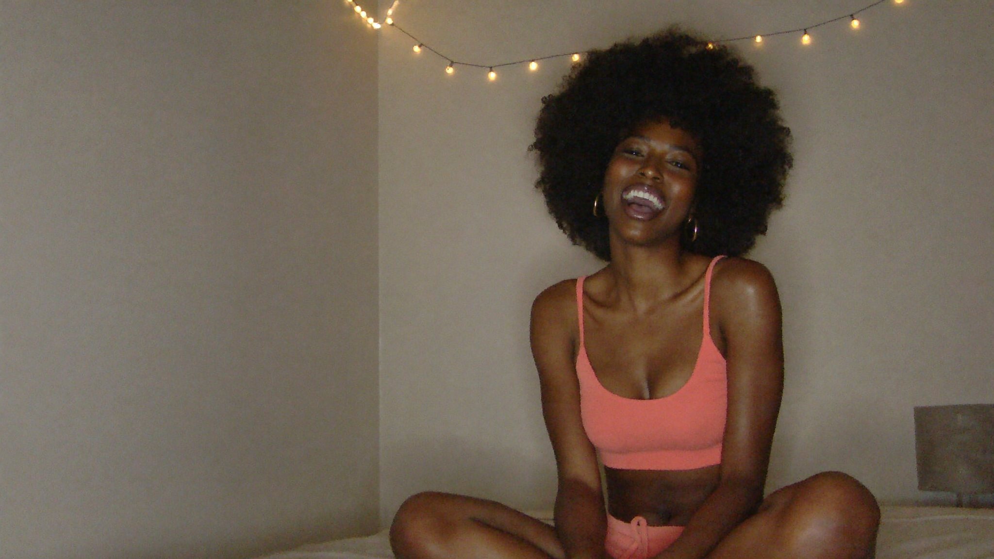 A Latina creator laughing in her room